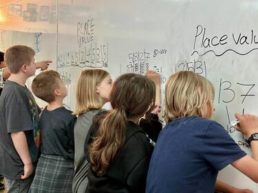 Student writing on a white board in classroom