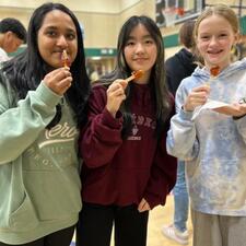 Three students standing, holding a sweet treat from the "Maple Man"