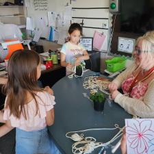 Helping Teacher sitting at a table with students in front of her.